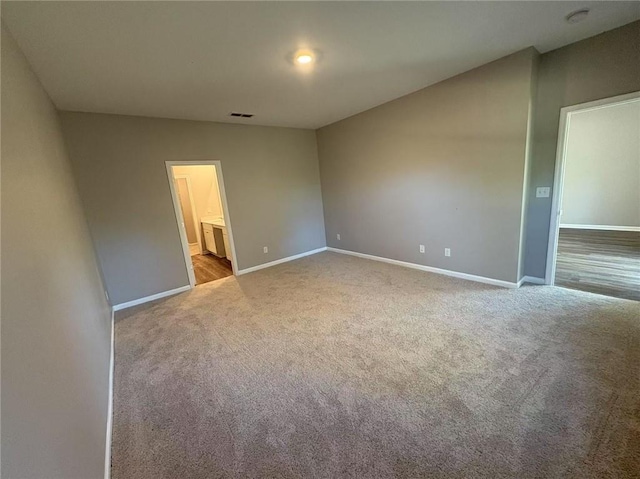 unfurnished bedroom featuring carpet floors, visible vents, ensuite bath, and baseboards