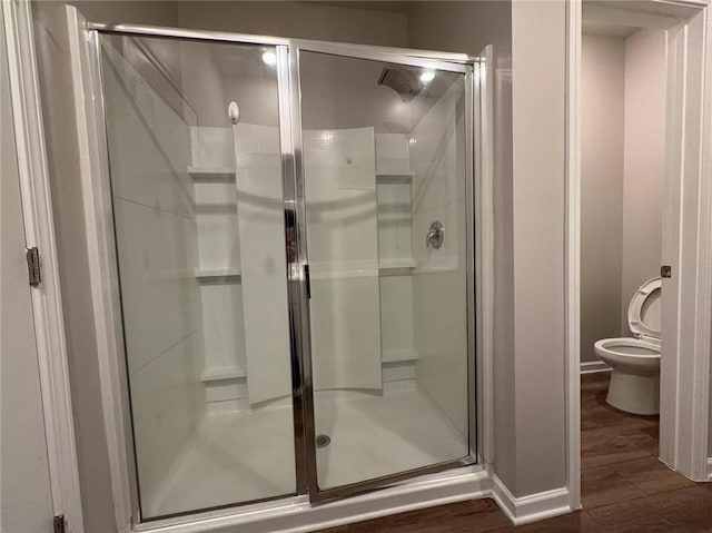 full bath featuring a stall shower, wood finished floors, and toilet