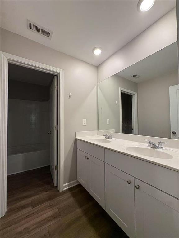 bathroom featuring double vanity, visible vents, a sink, and wood finished floors