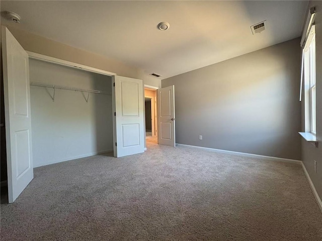 unfurnished bedroom featuring light carpet, baseboards, visible vents, and a closet