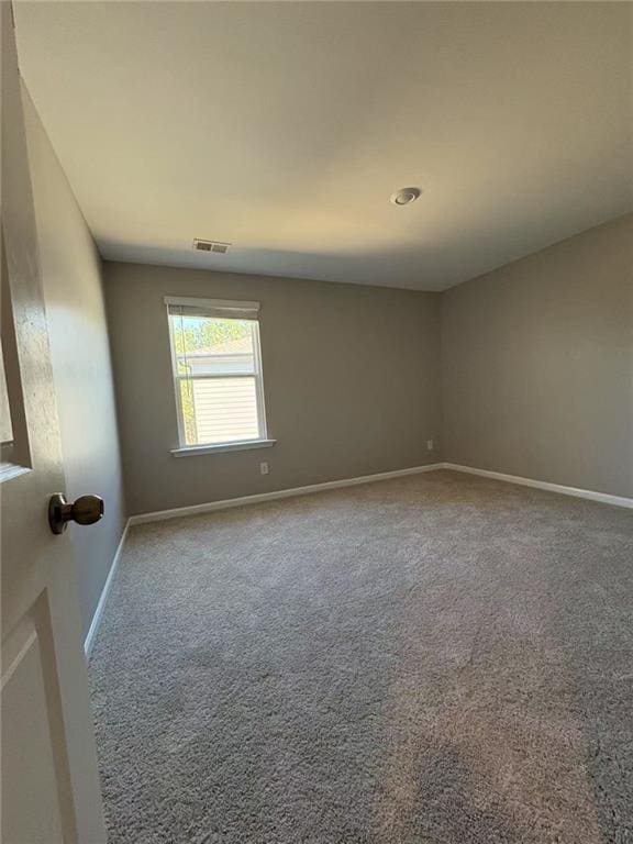 spare room featuring carpet flooring, visible vents, and baseboards