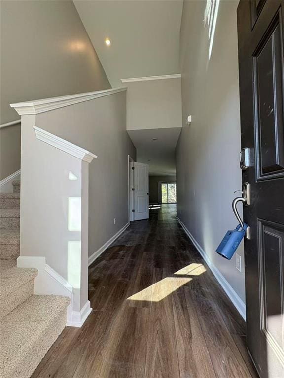 foyer entrance featuring stairway, wood finished floors, a towering ceiling, and baseboards