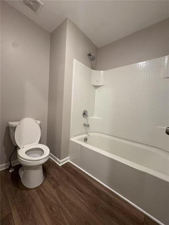 bathroom with bathing tub / shower combination, visible vents, toilet, wood finished floors, and baseboards