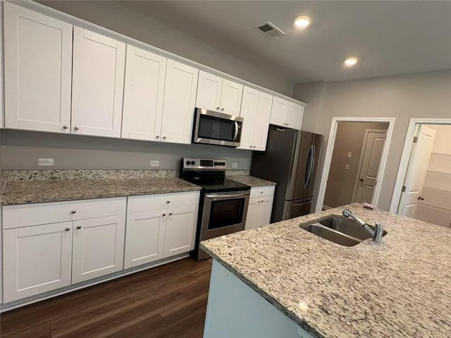 kitchen featuring dark wood finished floors, visible vents, appliances with stainless steel finishes, white cabinets, and a sink