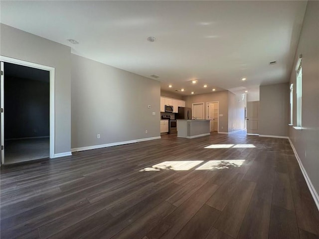 unfurnished living room with baseboards, dark wood-style flooring, and recessed lighting