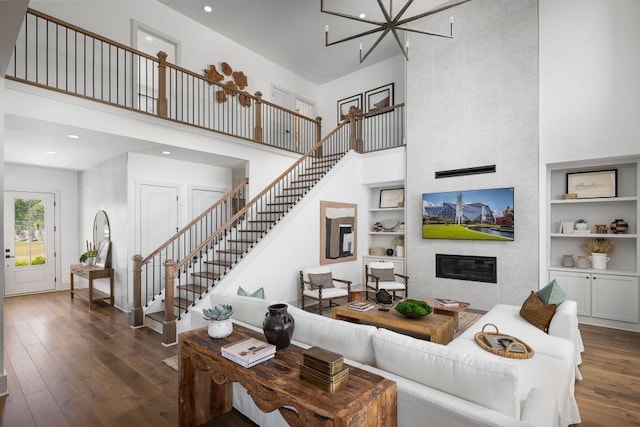 6930 Pond View Dr, Cumming, GA 30028 - living room featuring a towering ceiling, stairs, built in features, hardwood / wood-style flooring, and a tiled fireplace