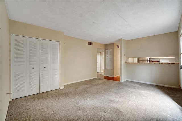 unfurnished bedroom featuring carpet floors, a closet, baseboards, visible vents, and a textured ceiling