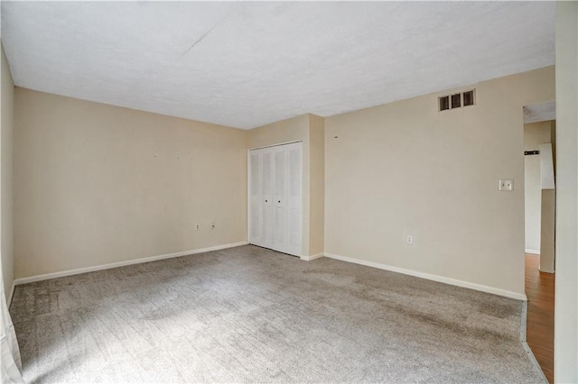 unfurnished room with carpet, visible vents, and baseboards