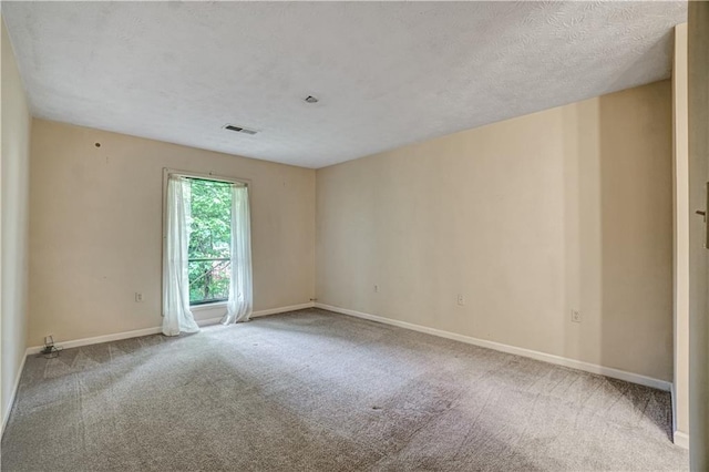 carpeted empty room with a textured ceiling, visible vents, and baseboards