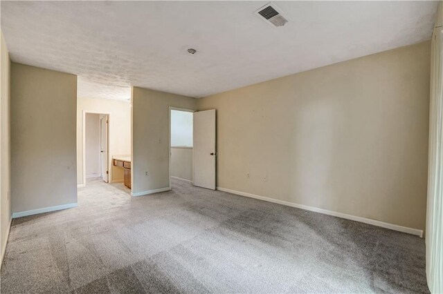 empty room with visible vents, light carpet, and baseboards