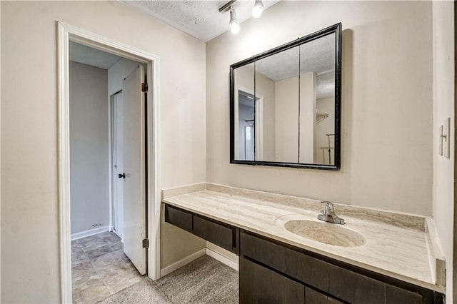 bathroom with a textured ceiling, vanity, and baseboards