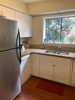 kitchen with stainless steel refrigerator, white cabinetry, sink, white dishwasher, and dark wood-type flooring