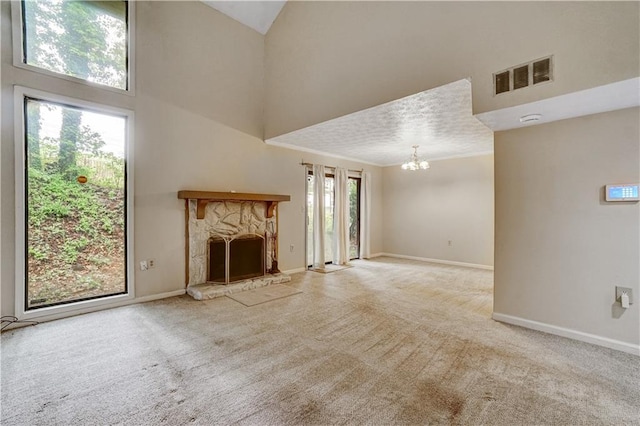 unfurnished living room featuring visible vents, carpet floors, a fireplace, a towering ceiling, and a notable chandelier