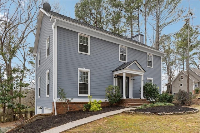 colonial inspired home featuring a front yard, fence, and a chimney