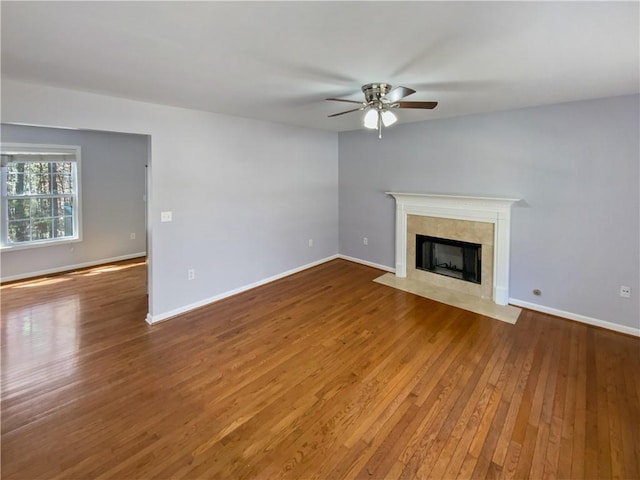 93 Wolfridge Ct, Dallas, GA 30132 - unfurnished living room featuring a tiled fireplace, baseboards, ceiling fan, and wood-type flooring