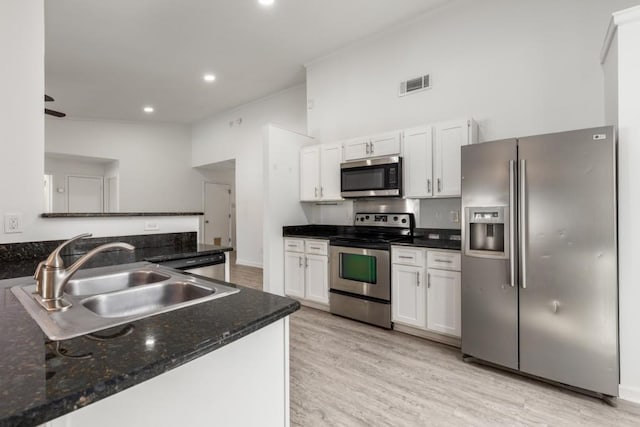 kitchen with appliances with stainless steel finishes, a sink, visible vents, and white cabinets