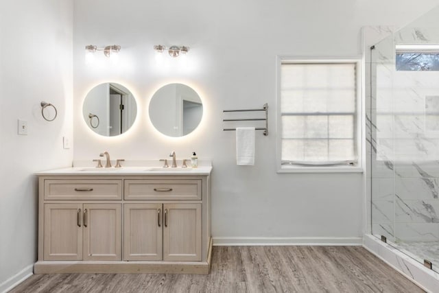 bathroom with wood finished floors, a sink, a marble finish shower, and baseboards