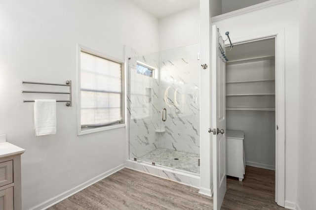 full bathroom with wood finished floors, a marble finish shower, vanity, and baseboards