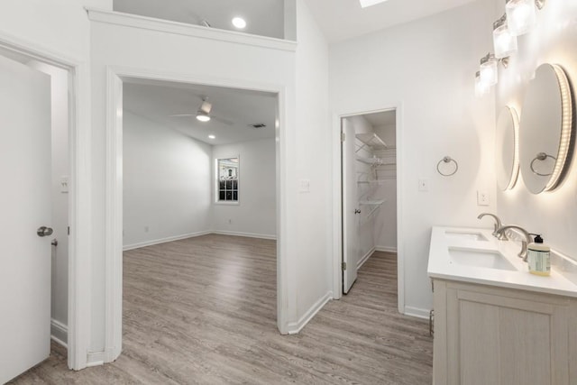 bathroom with a sink, a skylight, baseboards, and wood finished floors