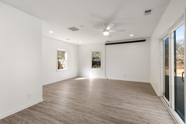 empty room featuring a healthy amount of sunlight, baseboards, visible vents, and wood finished floors