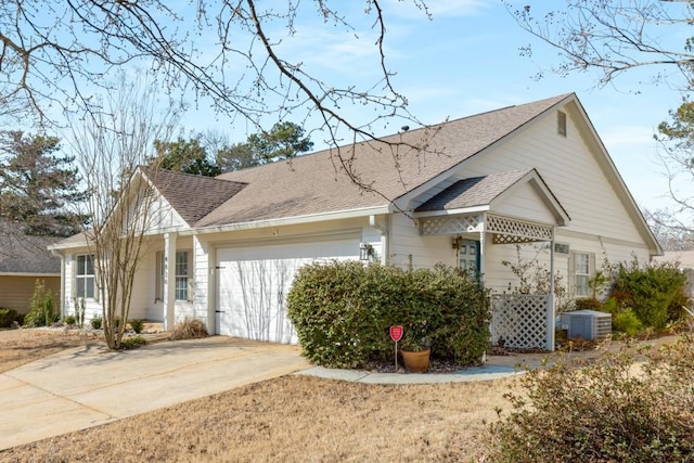 view of front of house with roof with shingles, driveway, central AC, and an attached garage