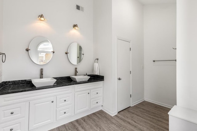 bathroom featuring double vanity, visible vents, a sink, and wood finished floors