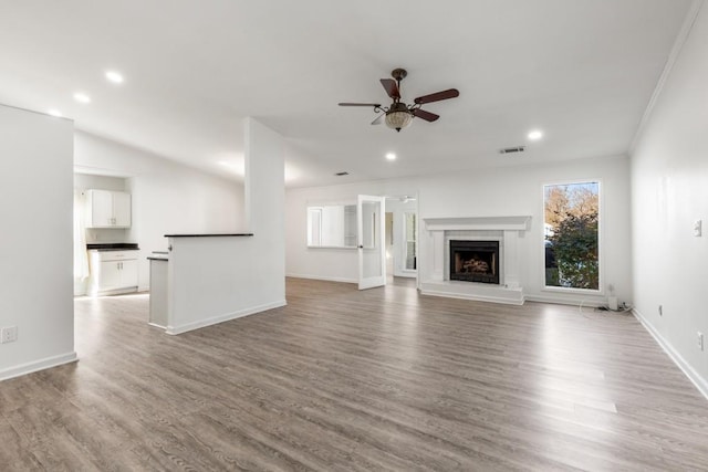 unfurnished living room with recessed lighting, a fireplace with raised hearth, ceiling fan, and wood finished floors