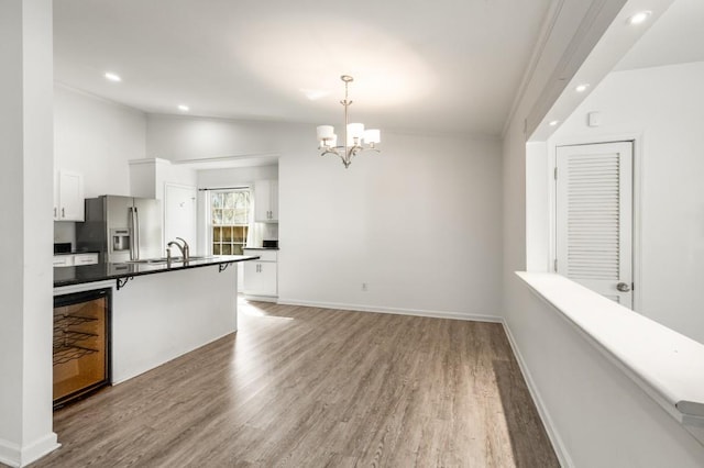 kitchen featuring wood finished floors, white cabinetry, vaulted ceiling, stainless steel refrigerator with ice dispenser, and dark countertops