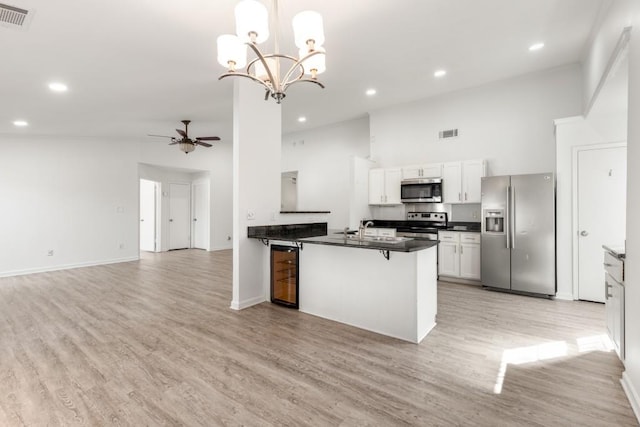 kitchen featuring visible vents, dark countertops, open floor plan, stainless steel appliances, and ceiling fan with notable chandelier