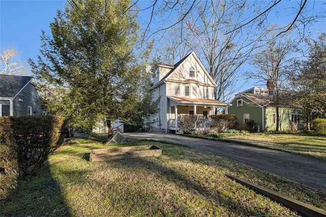 exterior space featuring aphalt driveway, a porch, and a front yard