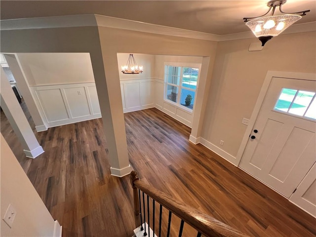 foyer featuring a notable chandelier, ornamental molding, and dark hardwood / wood-style flooring