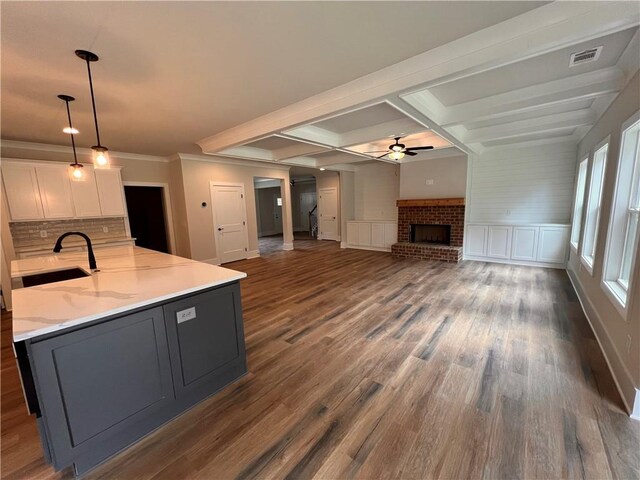 kitchen featuring white cabinetry, dark wood-type flooring, decorative light fixtures, and sink