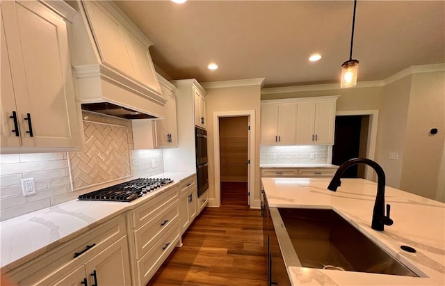 kitchen featuring stainless steel gas cooktop, sink, pendant lighting, custom exhaust hood, and light stone counters