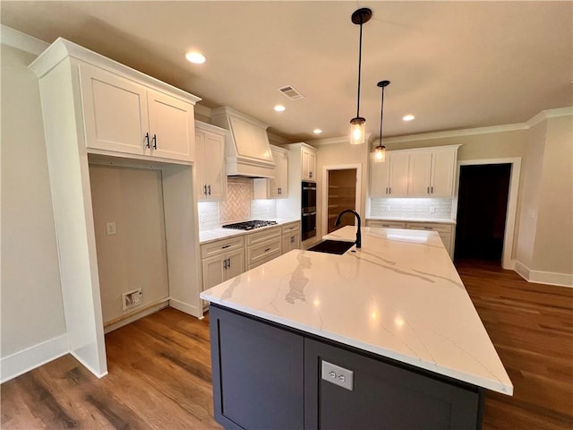 kitchen featuring a large island, sink, light stone countertops, decorative light fixtures, and white cabinets