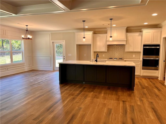 kitchen featuring double oven, white cabinetry, hanging light fixtures, and a healthy amount of sunlight