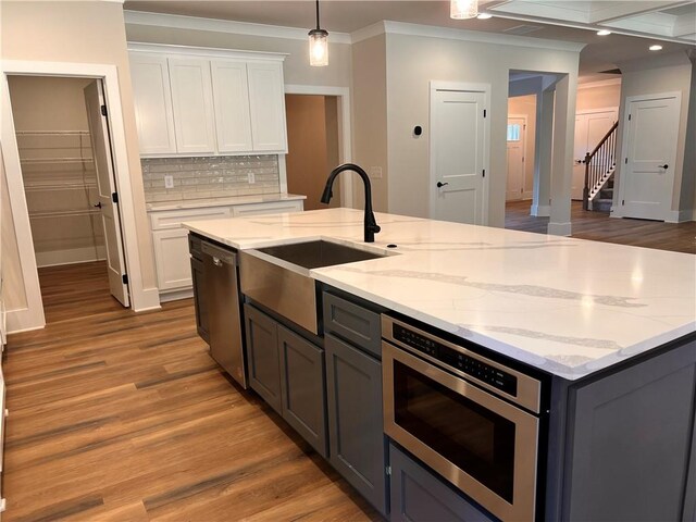 kitchen featuring appliances with stainless steel finishes, hardwood / wood-style floors, white cabinetry, and crown molding