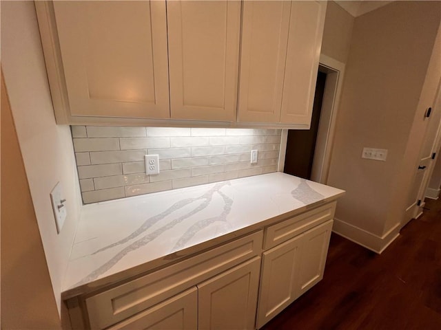 interior space with tasteful backsplash, light stone countertops, and dark hardwood / wood-style flooring