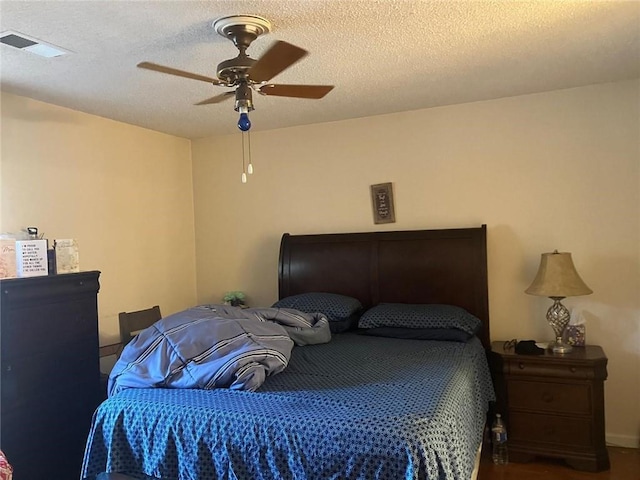 bedroom with a ceiling fan, visible vents, and a textured ceiling