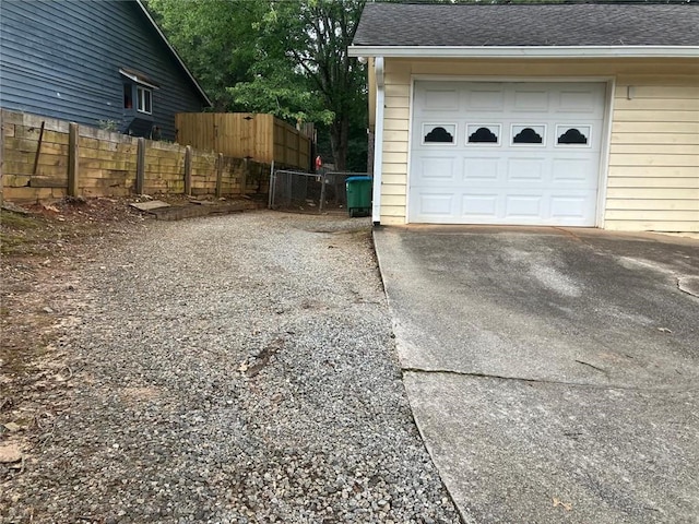 garage featuring driveway and fence