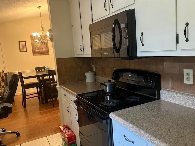 kitchen with tasteful backsplash, light countertops, white cabinetry, wood finished floors, and black appliances