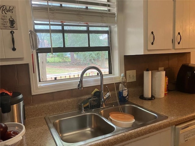 kitchen with a wealth of natural light, white cabinetry, a sink, and dishwasher