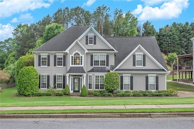 225 Ruby Forest Pkwy, Suwanee, GA 30024 - colonial home featuring stucco siding, a standing seam roof, a front lawn, a metal roof, and roof with shingles