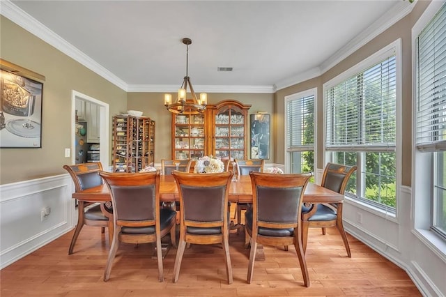 225 Ruby Forest Pkwy, Suwanee, GA 30024 - dining area with a chandelier, ornamental molding, light wood finished floors, and a wainscoted wall