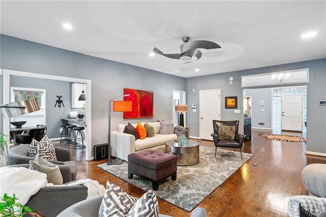 living room with ceiling fan with notable chandelier and hardwood / wood-style flooring