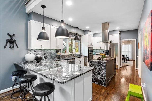 kitchen with tasteful backsplash, decorative light fixtures, dark stone countertops, white cabinets, and range hood