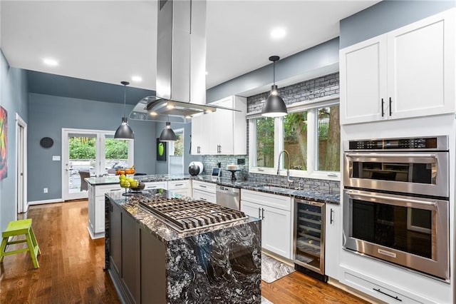 kitchen featuring kitchen peninsula, appliances with stainless steel finishes, dark stone counters, sink, and wine cooler