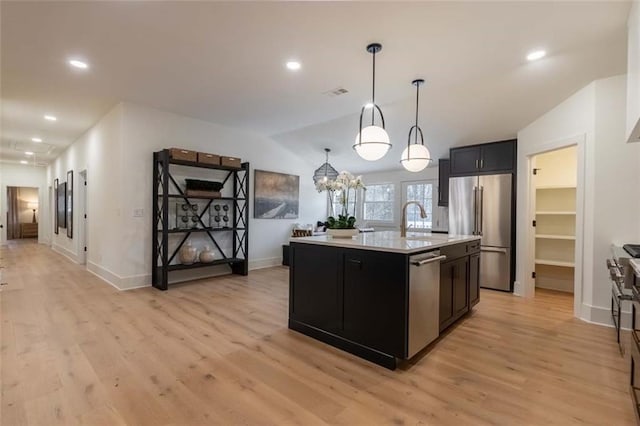 kitchen featuring a center island with sink, decorative light fixtures, stainless steel appliances, and vaulted ceiling