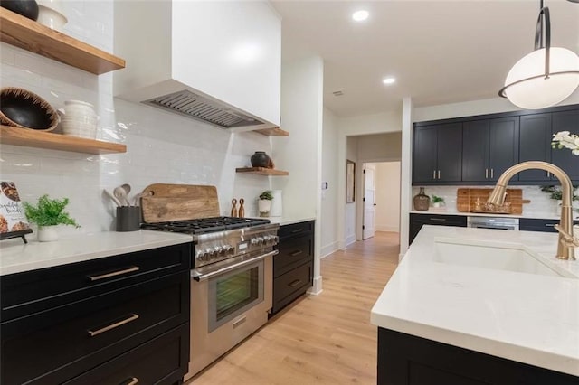 kitchen with backsplash, premium range hood, stainless steel range, pendant lighting, and light hardwood / wood-style floors