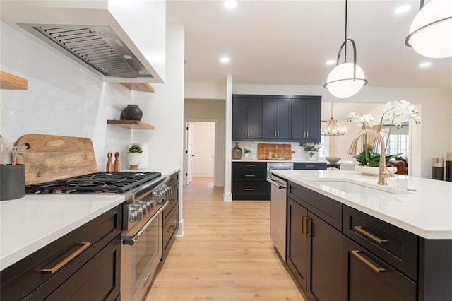 kitchen with sink, stainless steel appliances, hanging light fixtures, light hardwood / wood-style flooring, and extractor fan