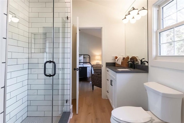 bathroom with hardwood / wood-style floors, vanity, toilet, and a shower with door